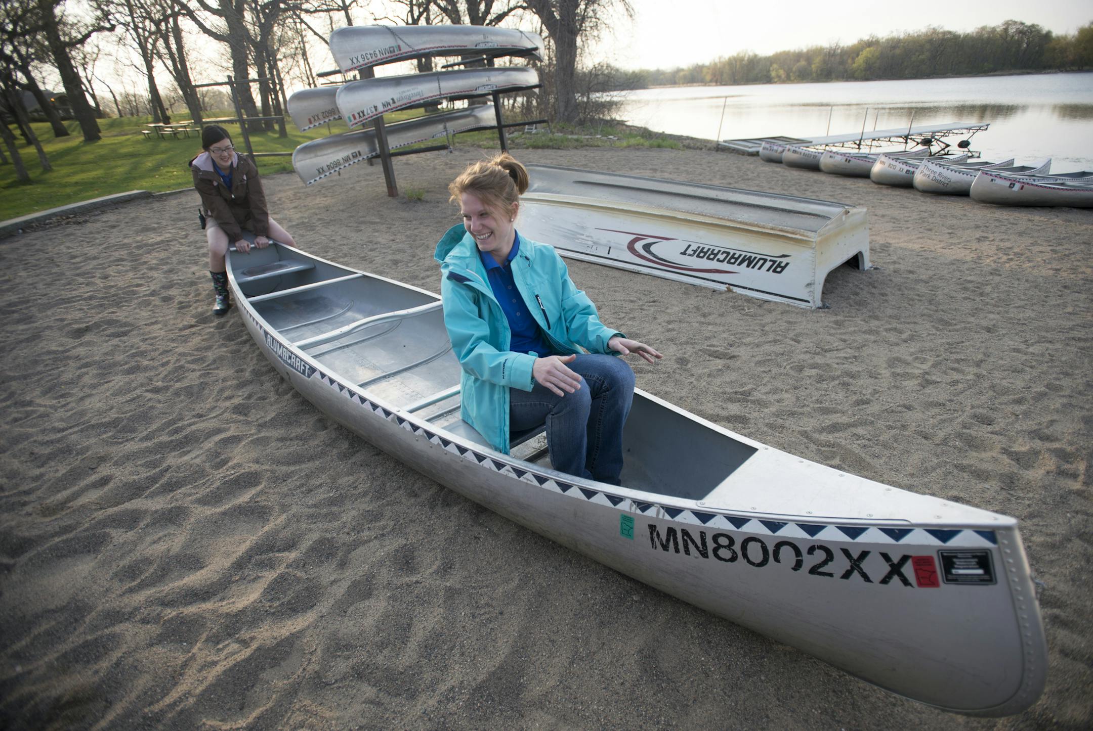 Outdoor recreational specialists McKayla Boelter, left, and Tashina Lahr demonstrate how to safely get into a canoe before taking out a small group onto Cleary Lake. ] (Aaron Lavinsky | StarTribune) aaron.lavinsky@startribune.com Three Rivers Parks District has figured out the full moon is a time of celebration. They offer some kind of night excursion for every full moon. This spring and summer it's canoeing. We photographed an hour-long canoe trip on Friday, May 1, 2015 at Cleary Lake.