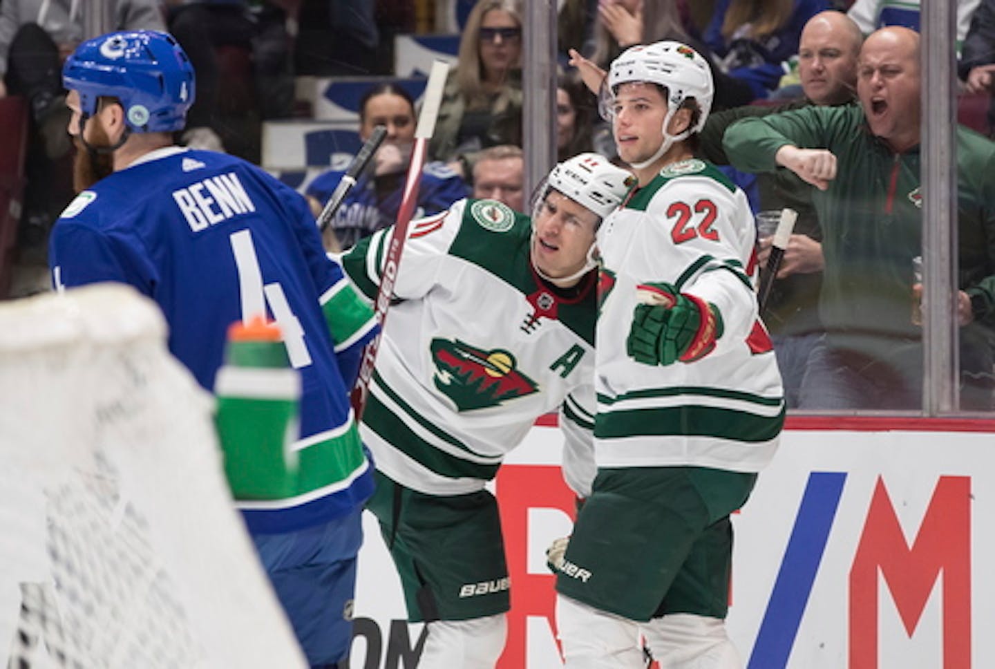 Minnesota Wild's Kevin Fiala, right, of Switzerland, and Zach Parise celebrate Fiala's goal as Vancouver Canucks' Jordie Benn skates past during the first period of an NHL hockey game Wednesday, Feb. 19, 2020, in Vancouver, British Columbia. (Darryl Dyck/The Canadian Press via AP)