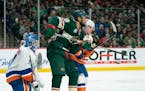 Minnesota Wild left wing Jordan Greenway (18) tries to deflect an incoming shot while defended by New York Islanders defenseman Devon Toews (25) in fr
