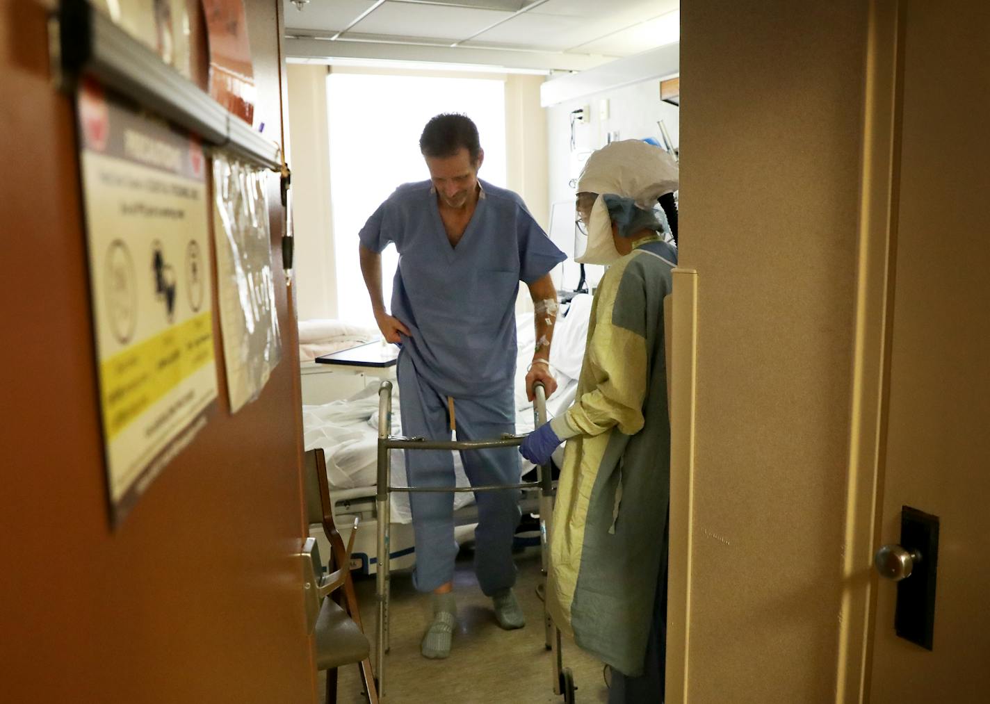 Under the watchful eye of nurse Sarah Neva, recovering COVID-19 patient Rick Huggins, 51, used a walker to sit in a nearby chair at Bethesda Hospital in St. Paul.