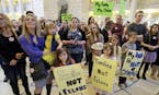 Polygamy advocate Vicki Darger, left, holds her daughter Tess, 2, while her other daughter Tori, 5, center left, holds a sign, as her husband's other 