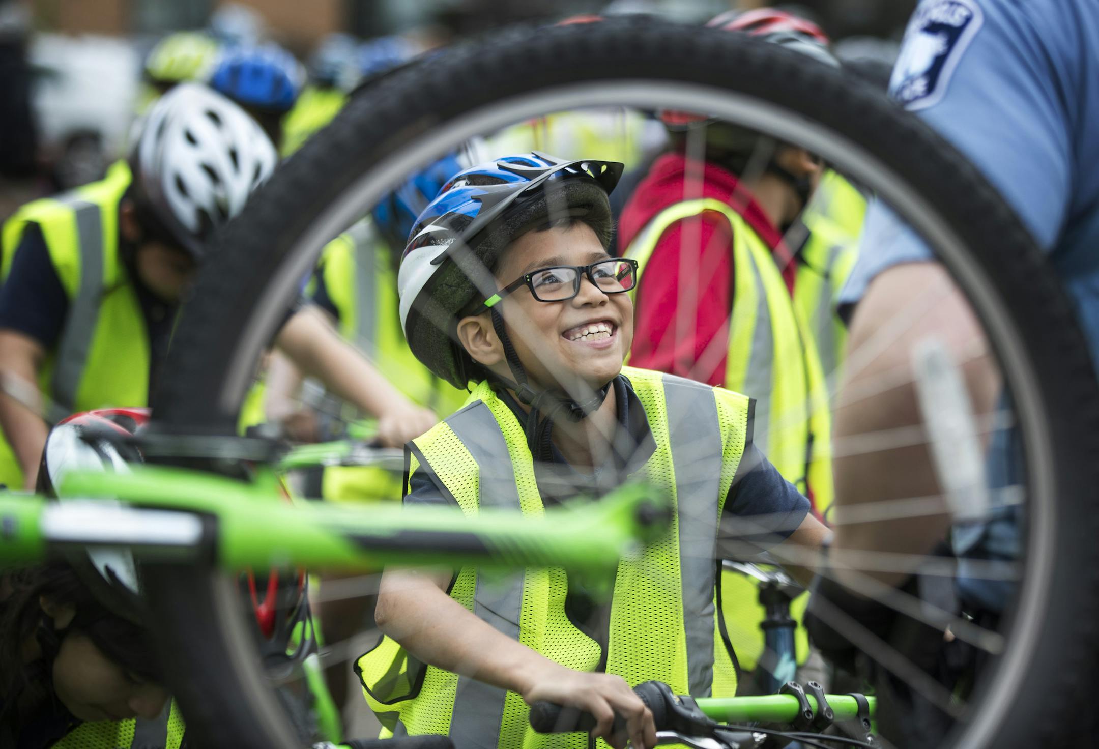 Yabel Rosado a forth grader at Nellie Stone Johnson school shared a laugh with a Minneapolis officer before riding with other students Wednesday May 9, 2018 in Minneapolis, MN. The bicyclist started their ride from the MPS Culinary & Wellness Services center in North Minneapolis for an hour bike ride to promote Wellness Week. ] JERRY HOLT • jerry.holt@startribune.com