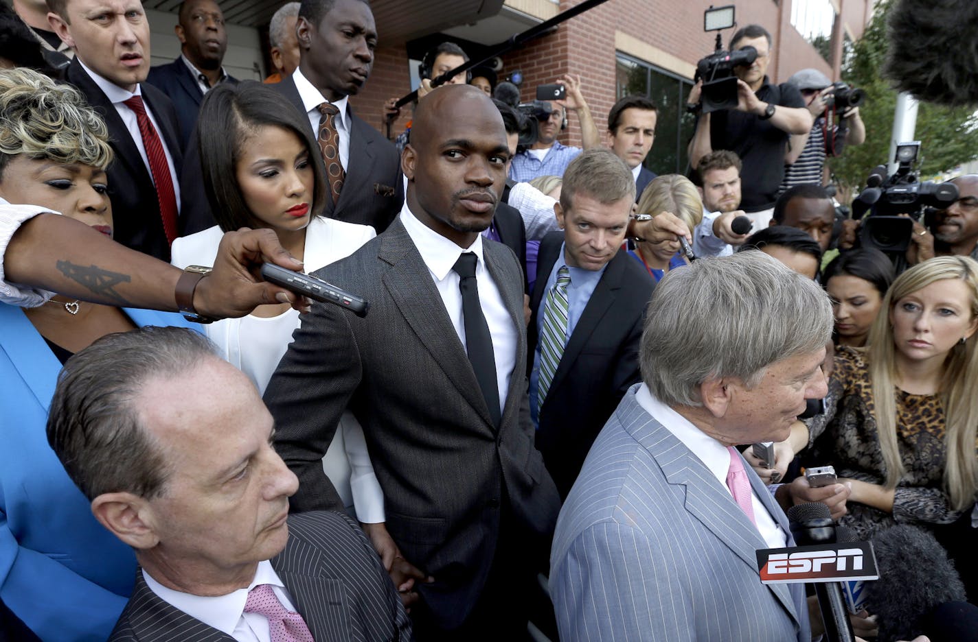 Minnesota Vikings running back Adrian Peterson, center, stands with his wife Ashley Brown Peterson, center left, and mother Bonita Jackson, far left, as they listen to Peterson's attorney Rusty Hardin, right, outside the courthouse after making his first court appearance Wednesday, Oct. 8, 2014, in Conroe, Texas. A Texas judge has tentatively set a Dec. 1 trial date for Peterson on a charge of felony child abuse for using a wooden switch to discipline his 4-year-old son. (AP Photo/David J. Phill