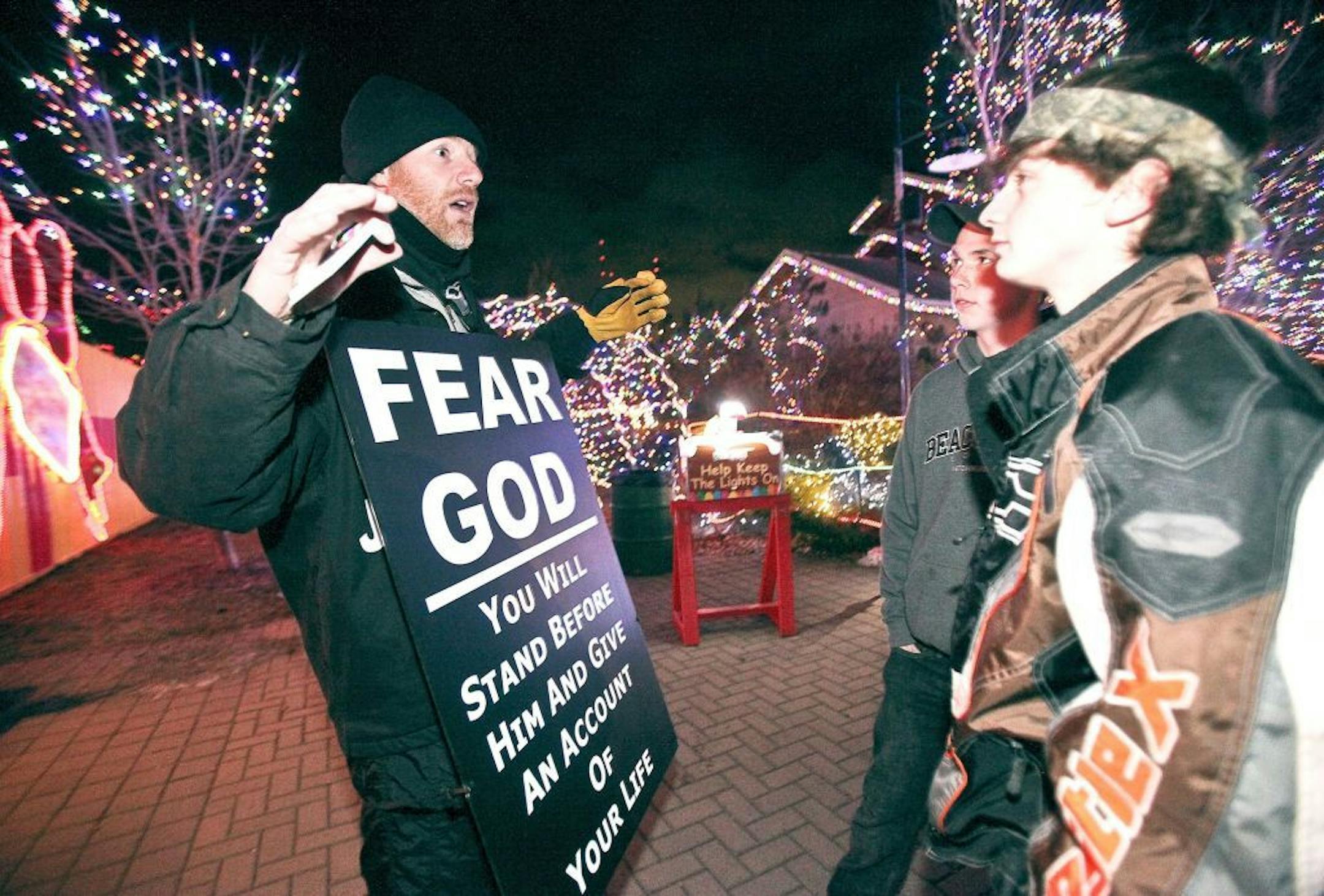In this Thursday, Dec. 6, 2012 photo, Steve Jankowski, of Duluth, left, preaches to Dennis Oberg, 15, and Justin McConnell, 17, both of Cloquet, during the Bentleyville display of lights at Bayfront Festival Park in Duluth, Minn. This is the second year in a row, a federal judge has ruled that preachers have free rein at the Bentleyville Tour of Lights in Duluth�s Bayfront Park. Nathan Bentley, who has staged the free holiday light display, says he's grown weary of the legal fight over access to