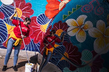 Anna Colakovic, a volunteer with Wells Fargo, rolls an anti-graffiti coating over a mural on Lake Street last month.