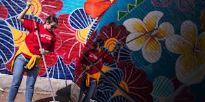 Anna Colakovic, a volunteer with Wells Fargo, rolls an anti-graffiti coating over a mural on Lake Street last month.