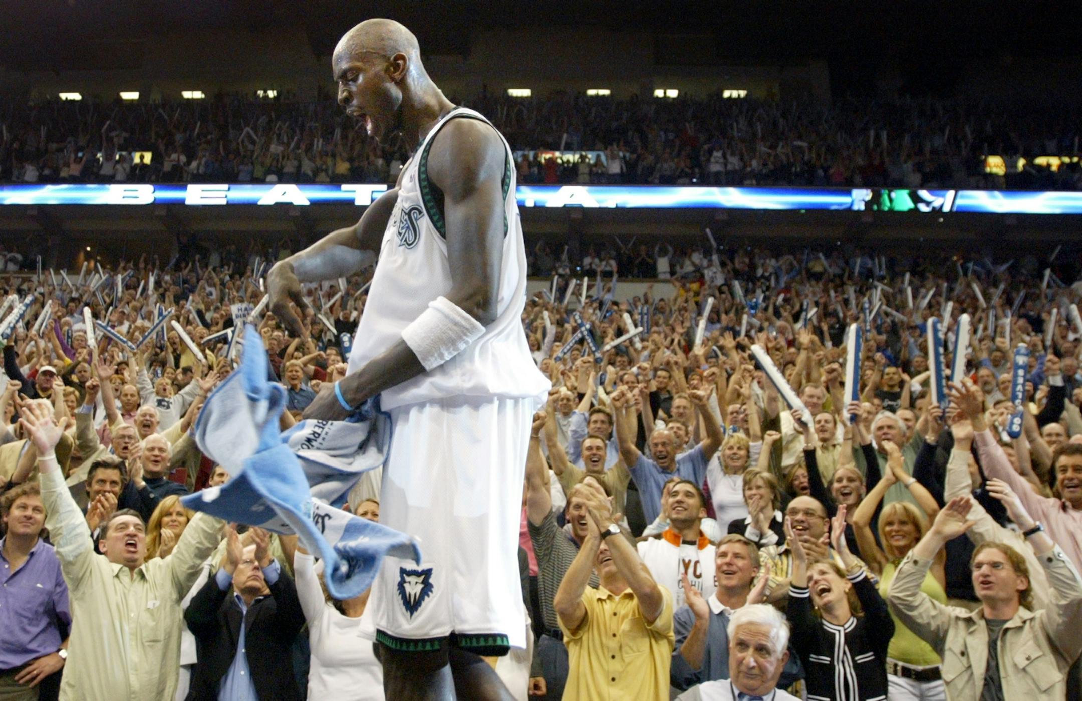 Fans cheer as Kevin Garnett walks across the press table at the end of the game. Minnesota beat Sacramento by a final score of 83-80. Sid Hartman is at right.