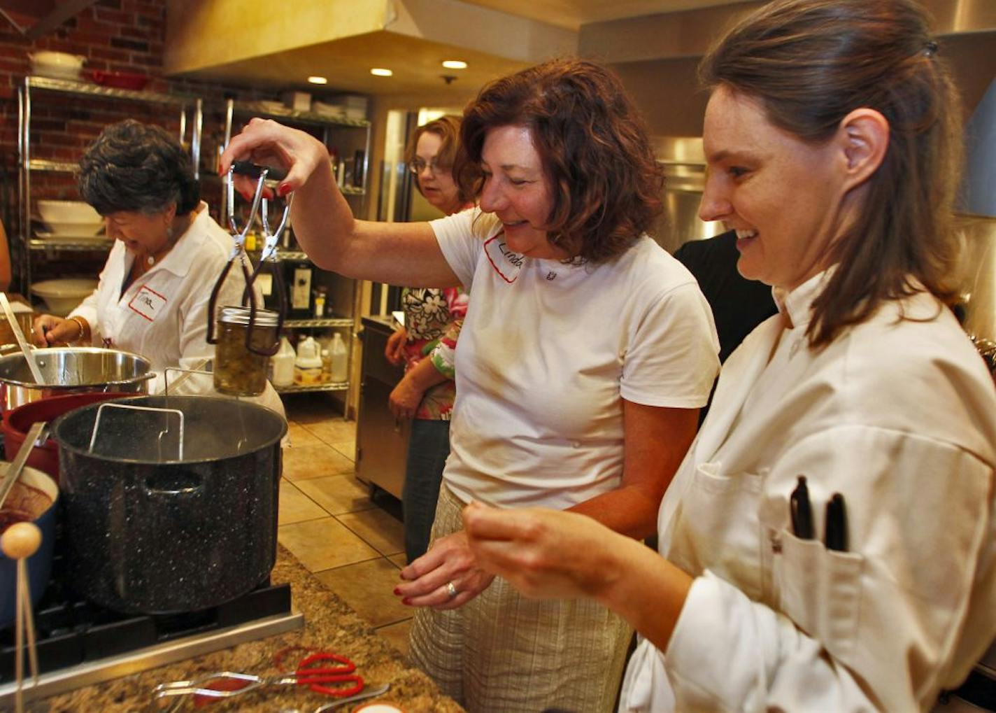 Jill Jacoby, right, taught a class at Chef's Gallery in Stillwater, coaching student Linda Shurden of Hudson, Wis., on the art of lifting canning jars from a pan of boiling water.