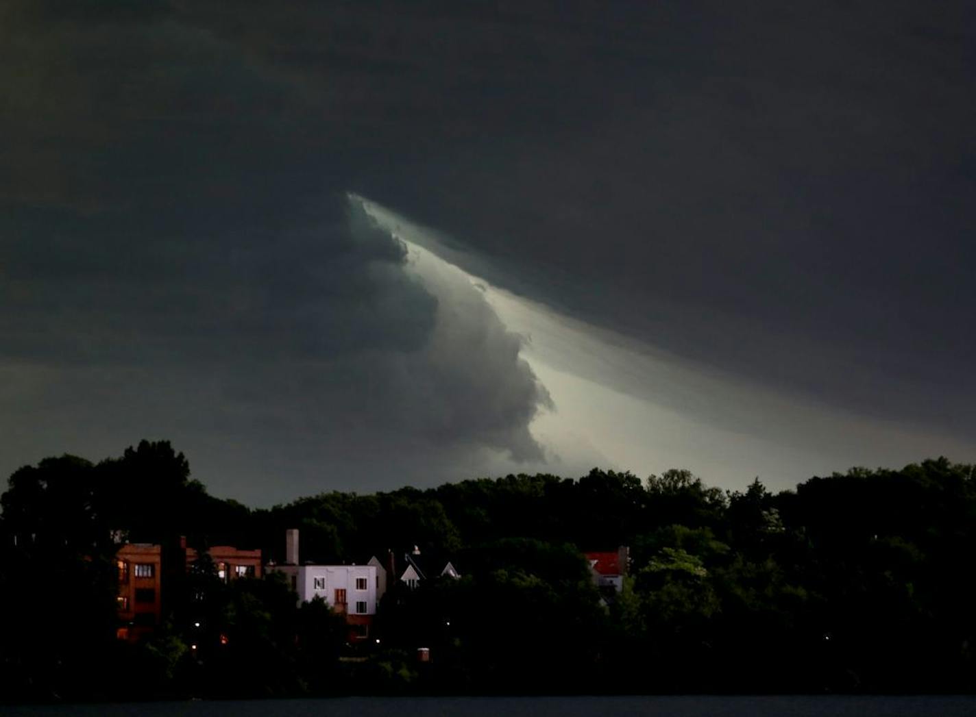 The sky briefly parts as a severe thunderstorm rolls east towards downtown Minneapolis, seen from the south side of Lake Harriet Sunday, June 11, 2017, in Minneapolis, MN.