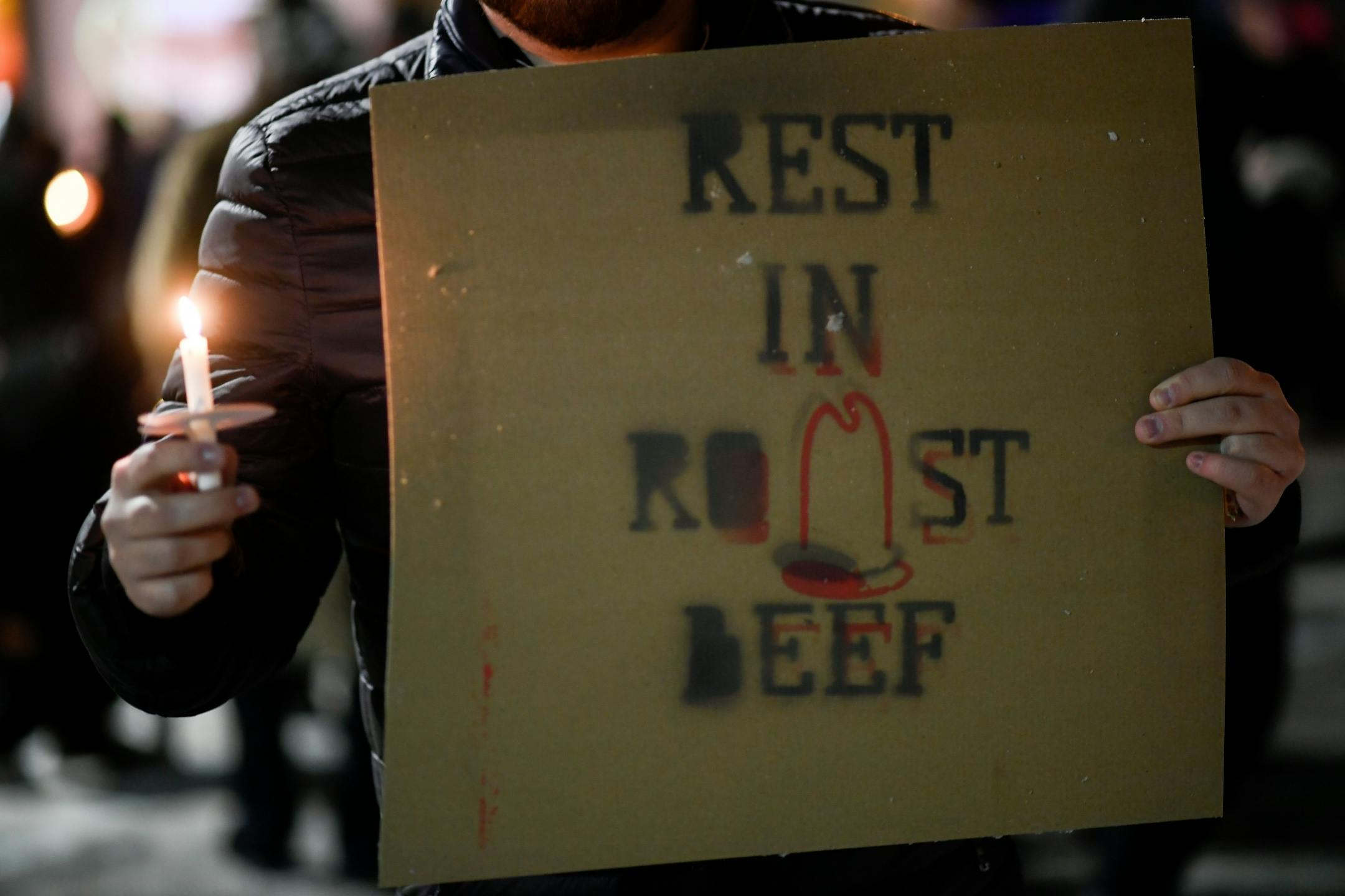 Matthew Felland held a candle and a "Rest in Roast Beef" sign as he took part in a vigil outside the now-close Uptown Arby's Friday night.