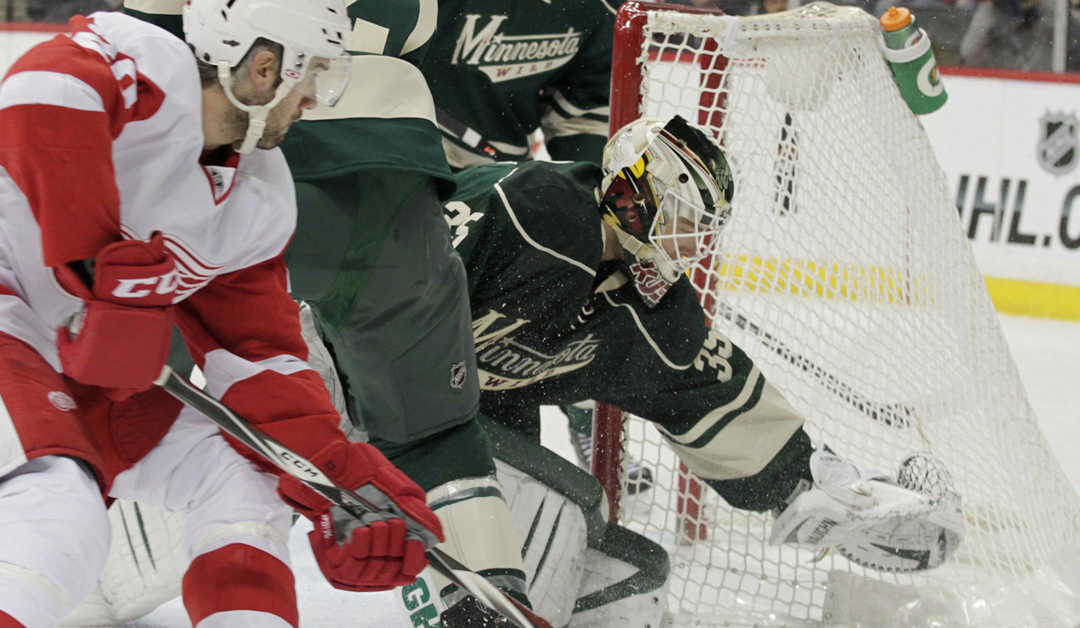 Minnesota Wild goalie Darcy Kuemper (35) dives for the puck as center Kyle Brodziak (21) defends as Detroit Red Wings Drew Miller (20) looks for a rebound during the second period of an NHL hockey game, Saturday, March 22, 2014, in St. Paul, Minn. Detroit won 3-2. (AP Photo/Paul Battaglia)