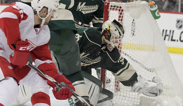 Minnesota Wild goalie Darcy Kuemper (35) dives for the puck as center Kyle Brodziak (21) defends as Detroit Red Wings Drew Miller (20) looks for a reb