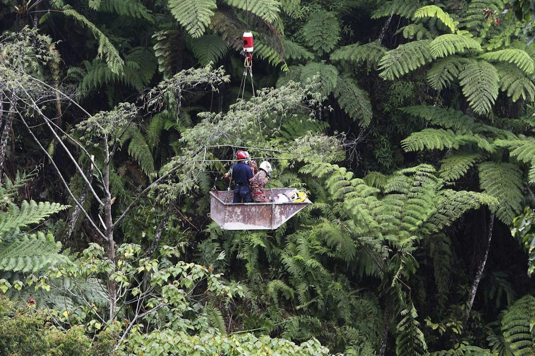 Malaysian emergency services personnel use a crane to rescue passengers after a bus carrying tourists and local residents fell into a ravine near the Genting Highlands, about an hour's drive from Kuala Lumpur, Malaysia, Wednesday, Aug. 21, 2013.