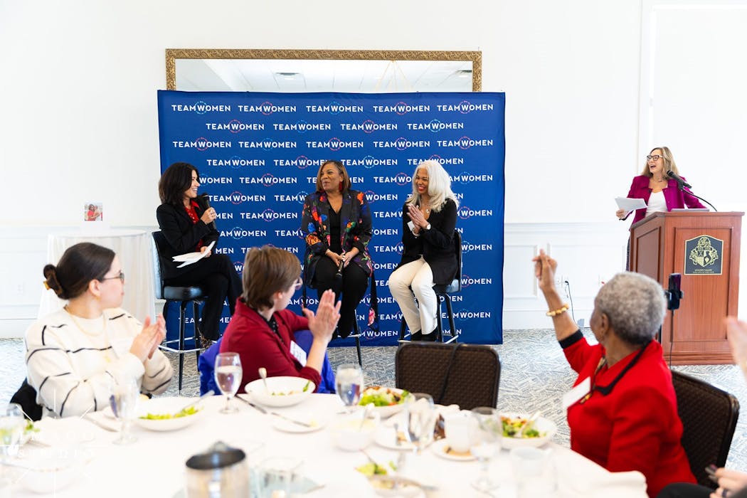 WCCO Anchor Amelia Santaniello and executives Chonda Smith Baker and Tonya Jackman Hampton (from left, seated on stools in back) and TeamWomen Executive Director Katy Burke (at podium, right) spoke at a power luncheon in February.