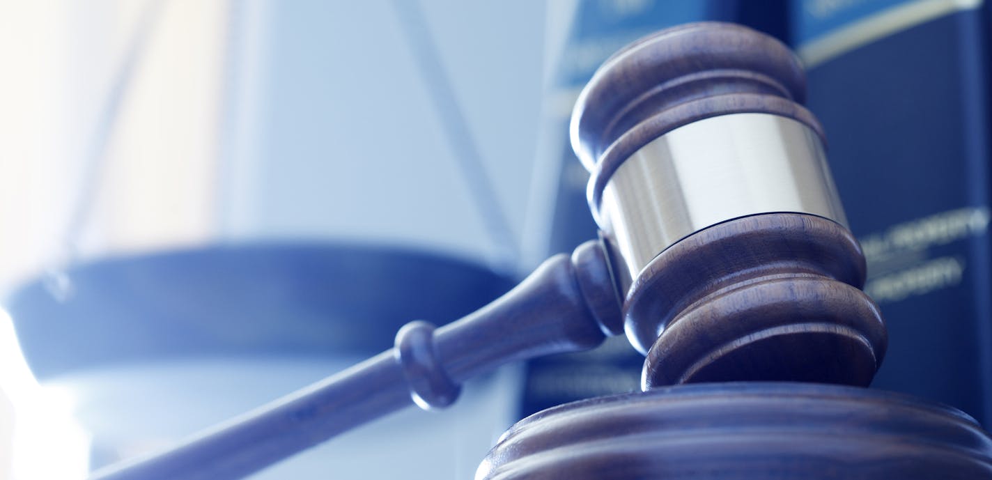 iStock
A gavel rests on its sounding block with a several law books and a justice scale out of focus in the background.