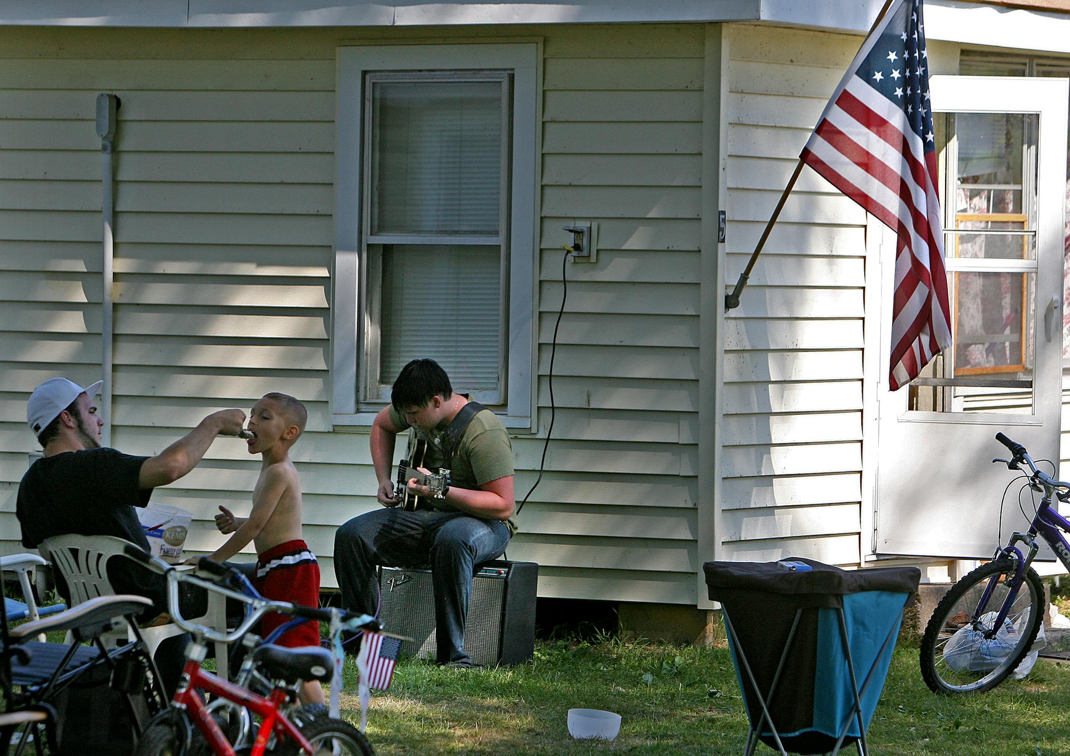 Rich Salsbury, left, fed Blake Griffin, 6, ice cream as his friend Mario Curro, right, played the guitar. The boys are family members of veterans who use the camp. The cabins were nurses' quarters when the camp was a veteran's hospital. Back then, veterans could stay for $1.25 a day.