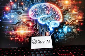 The OpenAI logo is seen displayed on a cell phone with an image on a computer monitor generated by ChatGPT's Dall-E text-to-image model, Friday, Dec. 