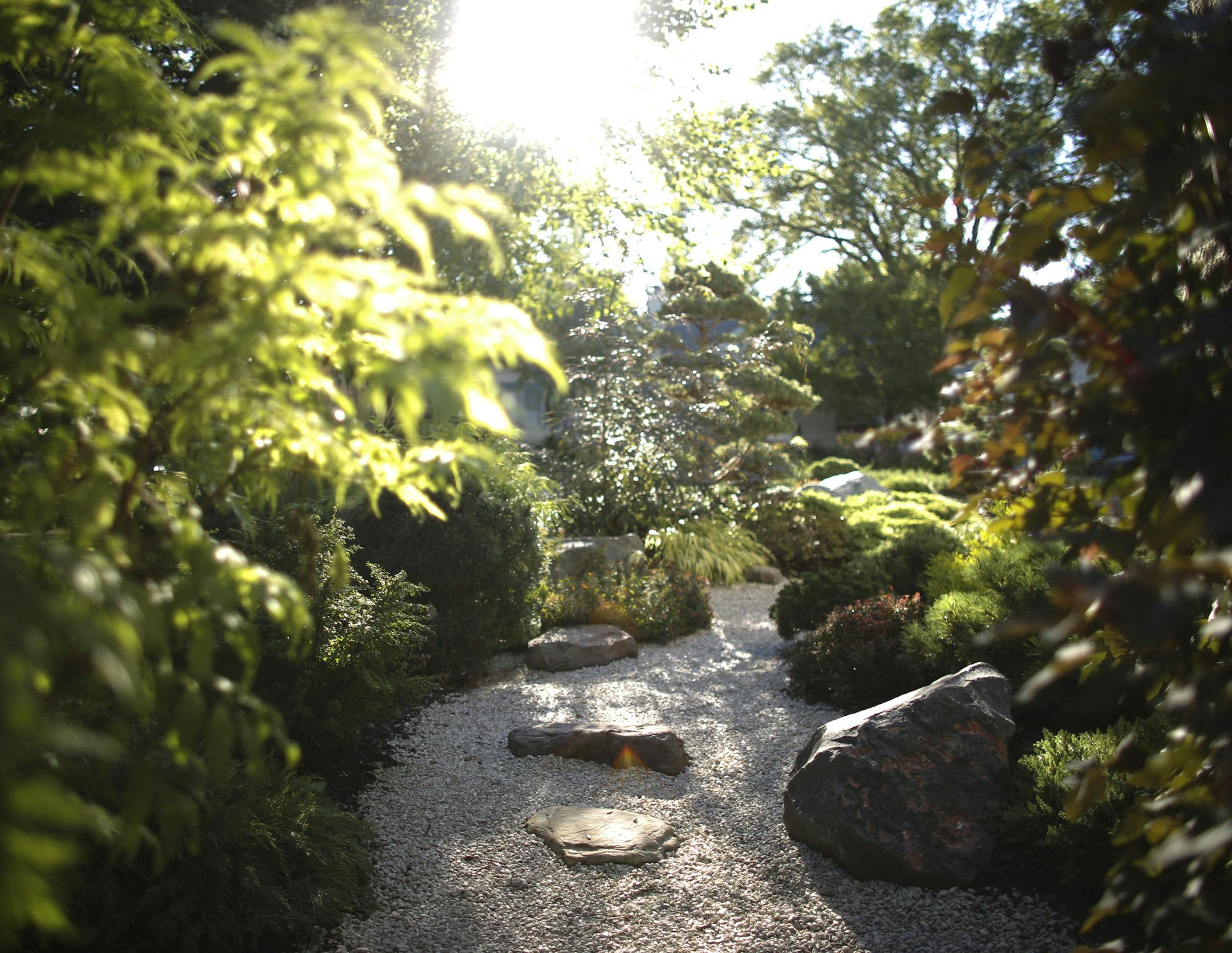 The stone path curves to “disappear” around the side of the house, which helps create the illusion of space and distance in the small lot.