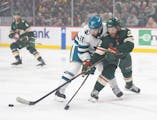 Wild right wing Ryan Hartman (38) passes to a teammate while defended by Sharks center Luke Kunin (11) in the first period Sunday.