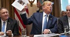 President Donald Trump holds up a photo of Rep. Ilhan Omar (D-Minn.) during a meeting at the White House in Washington on Tuesday, July 16, 2019. Trum