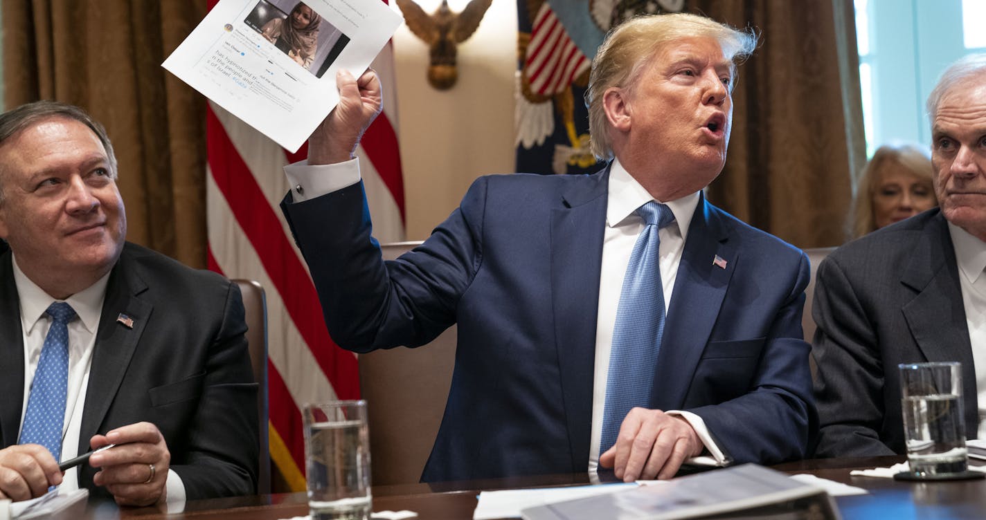 President Donald Trump holds up a photo of Rep. Ilhan Omar (D-Minn.) during a meeting at the White House in Washington on Tuesday, July 16, 2019. Trump denied that his tweets suggesting that Omar and three other minority congresswomen leave the country were racist, and implored House Republicans to reject a resolution up for a Tuesday evening vote that condemns his statements. (Doug Mills/The New York Times)