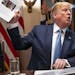 President Donald Trump holds up a photo of Rep. Ilhan Omar (D-Minn.) during a meeting at the White House in Washington on Tuesday, July 16, 2019. Trum