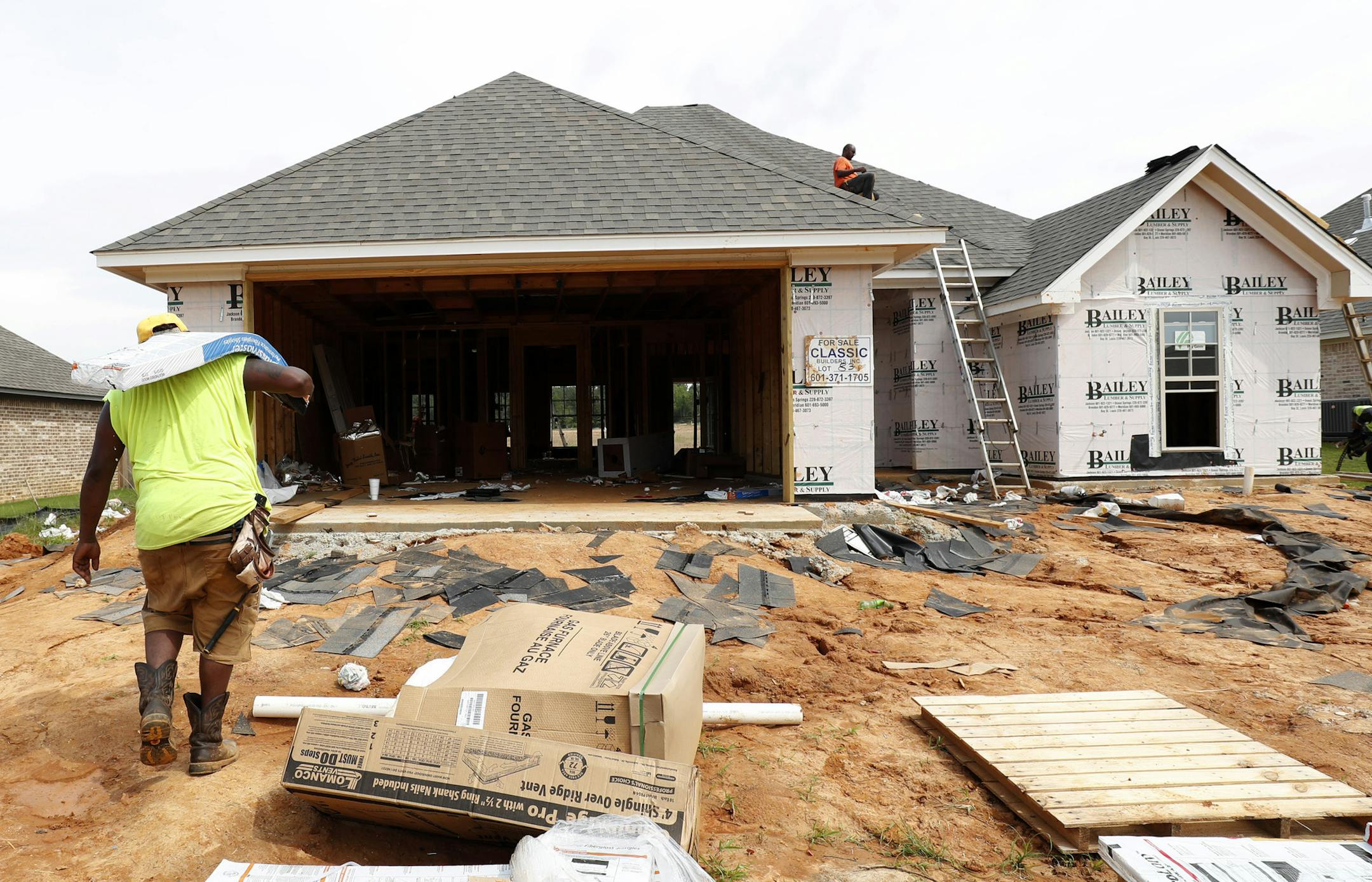 FILE - In this June 19, 2019, file photo a worker carries shingles for a roof of a house under construction in a Brandon, Miss., neighborhood. U.S. homebuilder stocks have been on a tear this year, with most individual companies on track to close out 2019 with gains well ahead of the broader market. (AP Photo/Rogelio V. Solis, File)