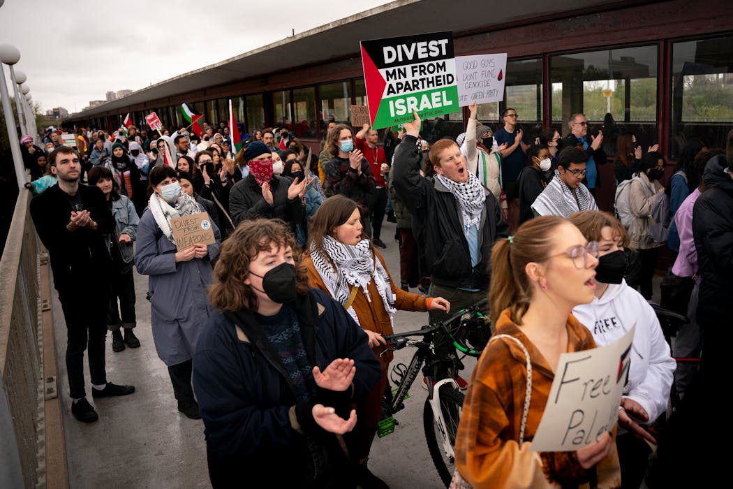Raven Dawson, holding the divest sign, chants while walking with other pro-Palestine demonstrators as they march across the U campus on the Washington Av. bridge Thursday evening.