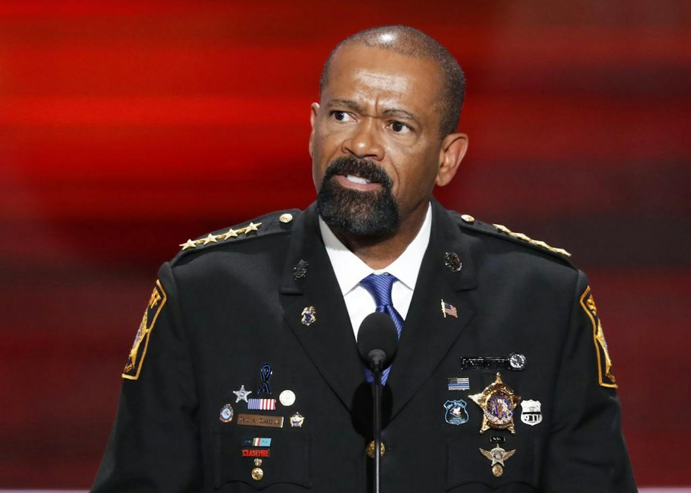 FILE - In this July 18, 2016 file photo, Milwaukee County Sheriff David Clarke speaks during the opening day of the Republican National Convention in Cleveland. Milwaukee resident Dan Black says Clarke had deputies question him after a flight because he shook his head at the lawman, who has gained national prominence for supporting Donald Trump. Black says in a complaint submitted to the sheriff's website, he shook his head because Clarke was wearing Dallas Cowboys clothes on Sunday, Jan. 15, 20