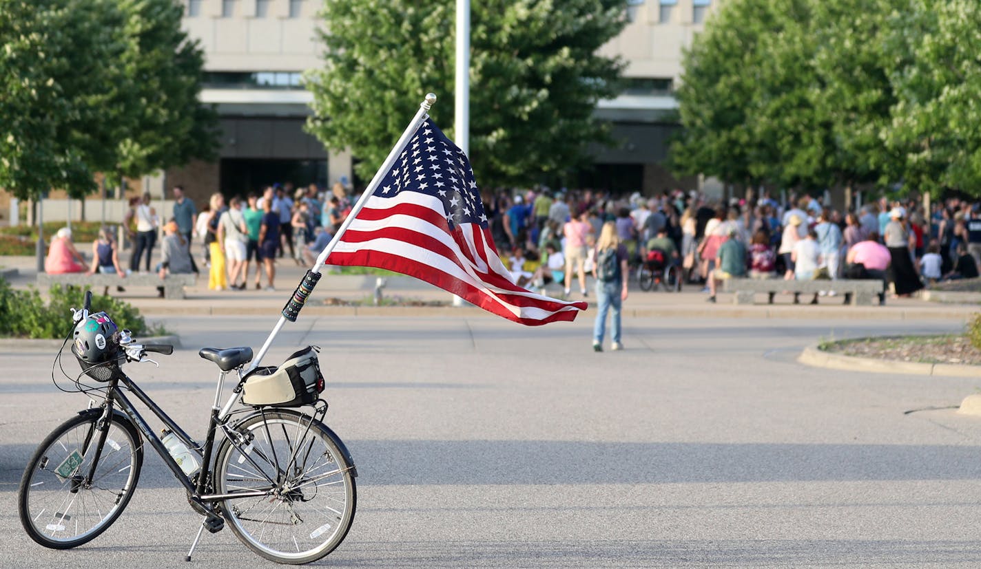 Joldy Wynen of Minneapolis, who rode her bike from Minneapolis, photographed her bike with the flag before the start of the Lights for Liberty vigil "to expose the inhumane conditions faced by immigrants in detention and holding facilitates," outside Whipple Federal Building Friday, July 12, 2019, in Fort Snelling, MN. She said she had come in part because of the "horrific conditions," for immigrants caught crossing the border.]
DAVID JOLES &#x2022; david.joles@startribune.com Lights for Liberty