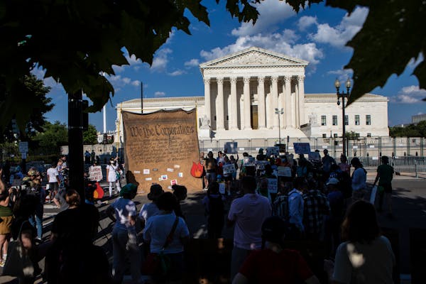Activists gather outside the Supreme Court building in Washington following a decision that sharply curtailed existing federal climate regulations on 