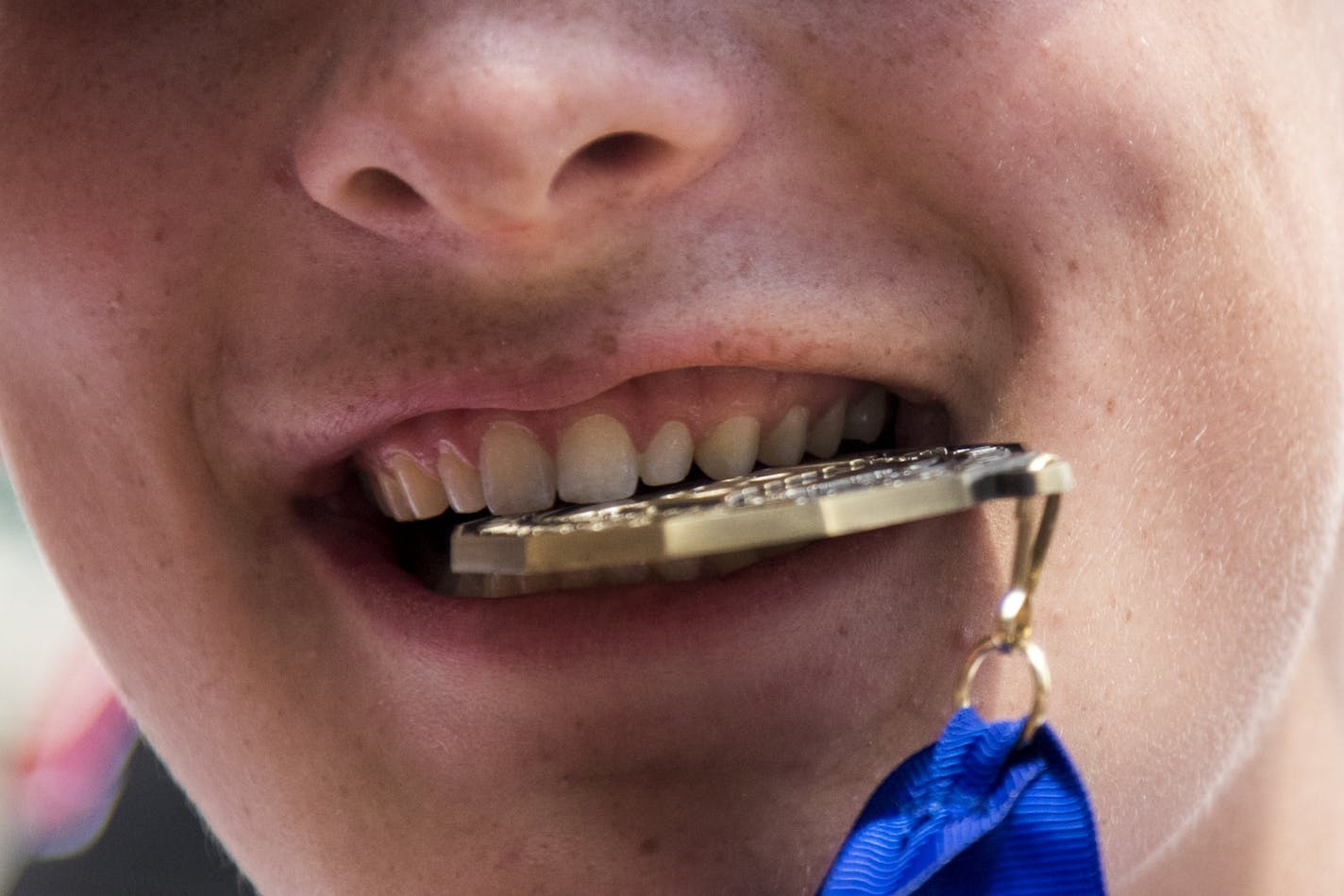 Roddy MacDonald of Minnehaha Academy bites his gold medal after Class 2A baseball title game at Target Field.