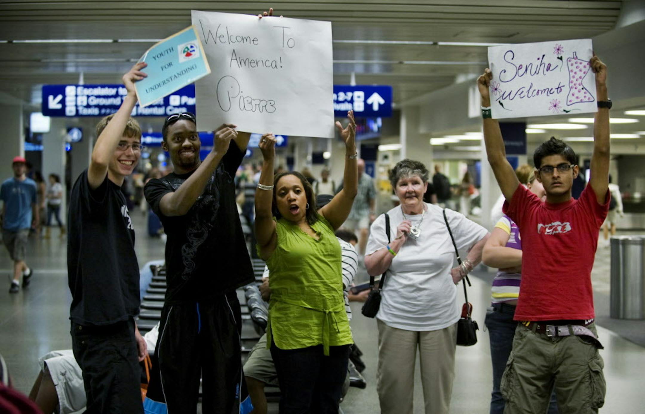 DAVID BREWSTER &#xef; dbrewster@startribune.com Wednesday 08/18/10 Minneapolis (airport) Marcy Werness is a volunteer with Youth for Understanding, and goes to the airport to personally greet every foreign exchange student who arrives for their program. She's been doing this for about 15 years. IN THIS PHOTO: ] Marcy Werness, in white second from right, waits for the arrival of 2 foreign students at the baggage pickup area at the airport. She is accompanied by other foreign students and sponsori