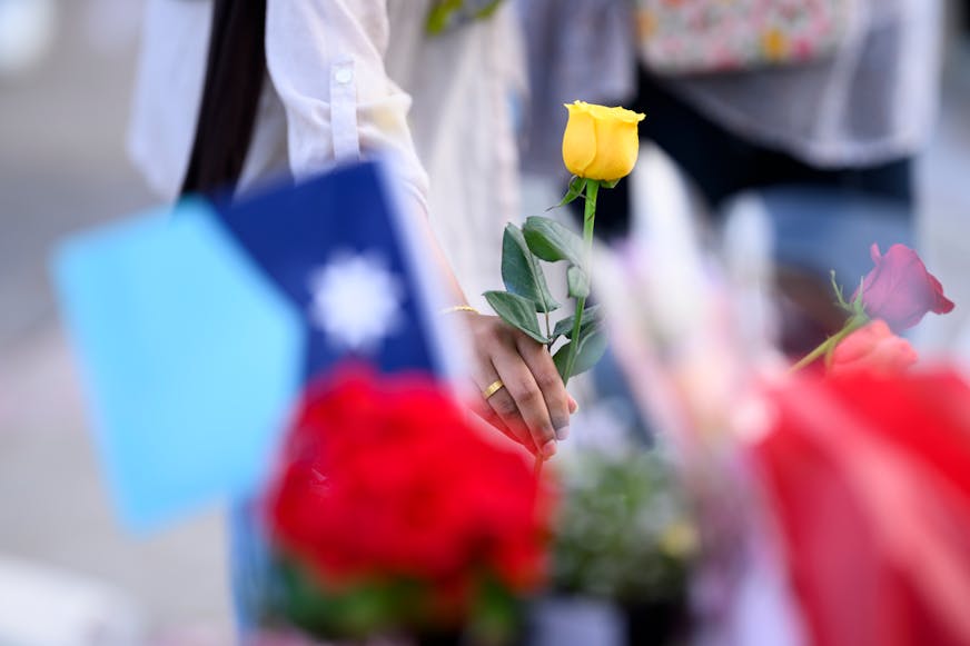 Arshia Hussain, of Brooklyn Park, places a flower on a memorial during a candlelight vigil on June 18 at the State Capitol for Melissa and Mark Hortman.