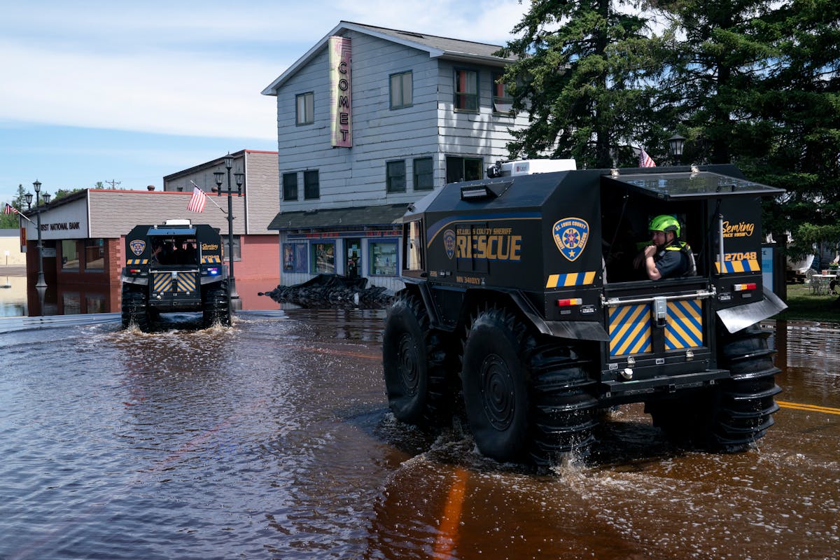 St. Louis County Sheriff's Office rescue vehicles cruise down flooded streets in Cook, Minn., on June 21, passing in front of the flooded Comet Theate