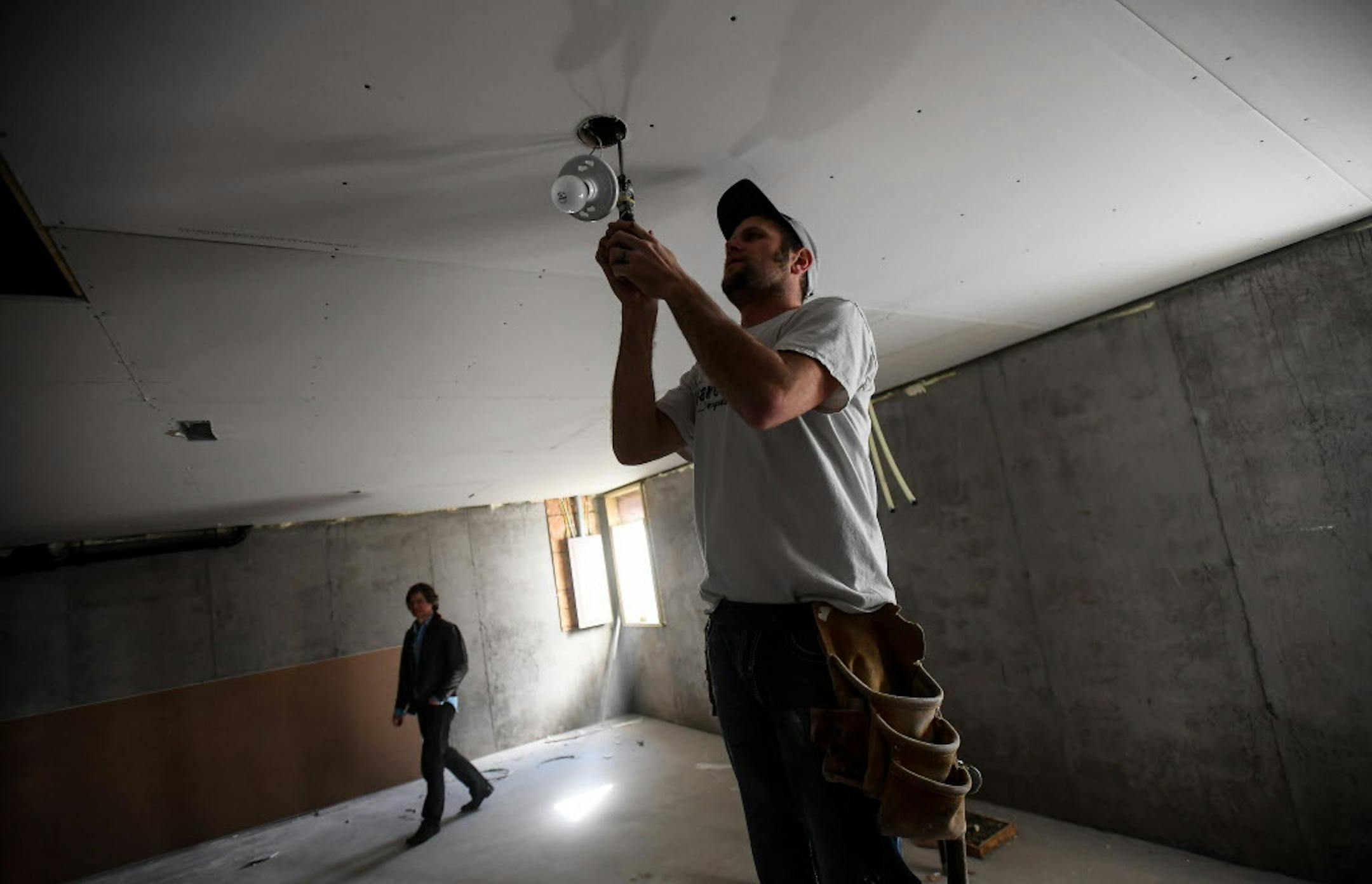 Contractor Doug DeFlorin installed a lighting fixture in the basement of an almost-finished new home in northeast Minneapolis Friday afternoon. Realtor and lot owner Chris Harrington surveyed the work being done in the basement in the background. ] AARON LAVINSKY &#xef; aaron.lavinsky@startribune.com Housing construction -apartments and single-family houses - in the Twin Cities metro soared during March, according to a monthly report from the Builders Association of the Twin Cities. Realtor Chri