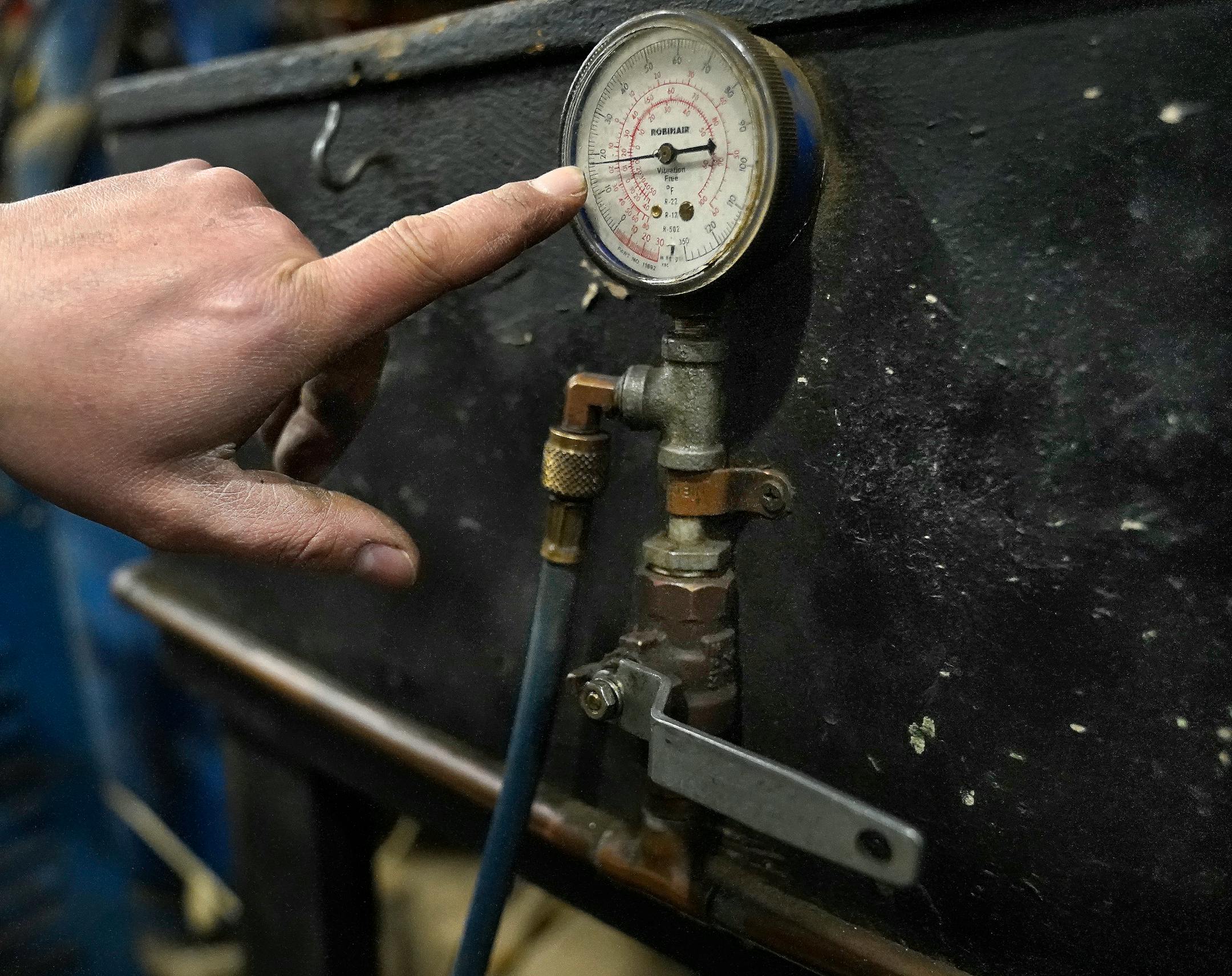 J.R.'s Advanced Recyclers dock supervisor Erick Perez points to a gauge that reads almost 20 ounces of a hydrofluorocarbon-based refrigerant is being sucked from an old refridgerator during the recycling process.