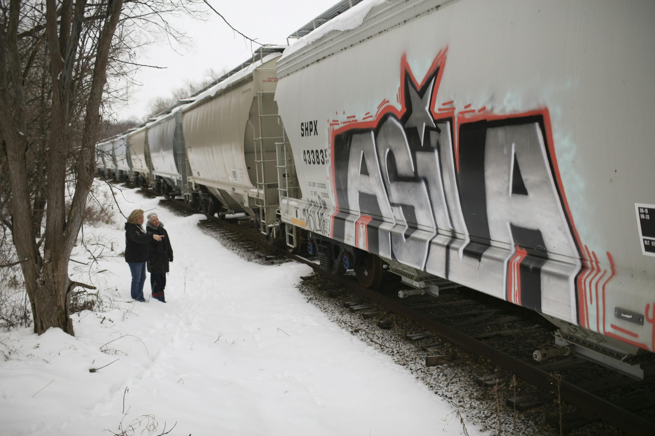 Pam Steinhagen, left, and a neighbor, Dee Volz looking at graffiti on one of the rail cars parked behind the houses on their street Wednesday afternoon.