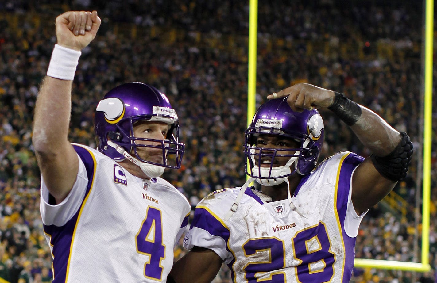 Brett Favre (4) and Adrian Peterson (28) celebrate after Favre threw a touchdown pass against the Green Bay Packers during an NFL football game in Green Bay, Wis.