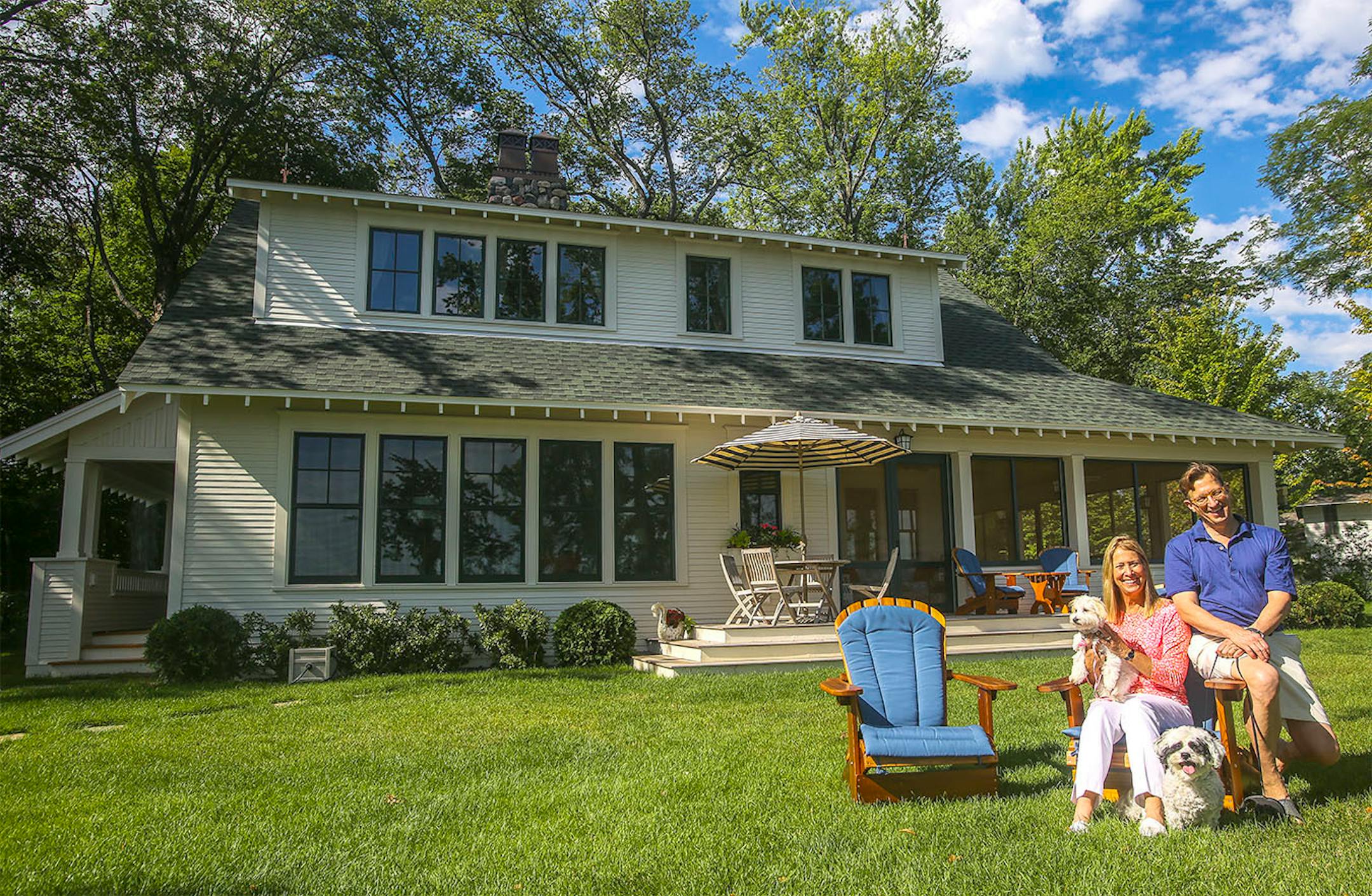 Leni and David Moore with their dogs on the Lake Minnetonka side of their newly built Crane Island cottage, which was designed to blend with the decades-old neighboring homes by David Heide Design Studio.
