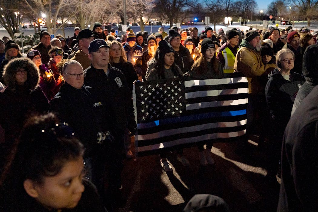 Nely Guerra-Rivera and Hailey Nelson hold a flag together during a vigil in Burnsville Sunday evening. 