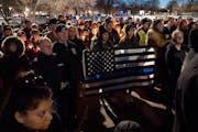 Nely Guerra-Rivera and Hailey Nelson held a flag together at a vigil for the two police officers and a firefighter-paramedic killed in Burnsville that