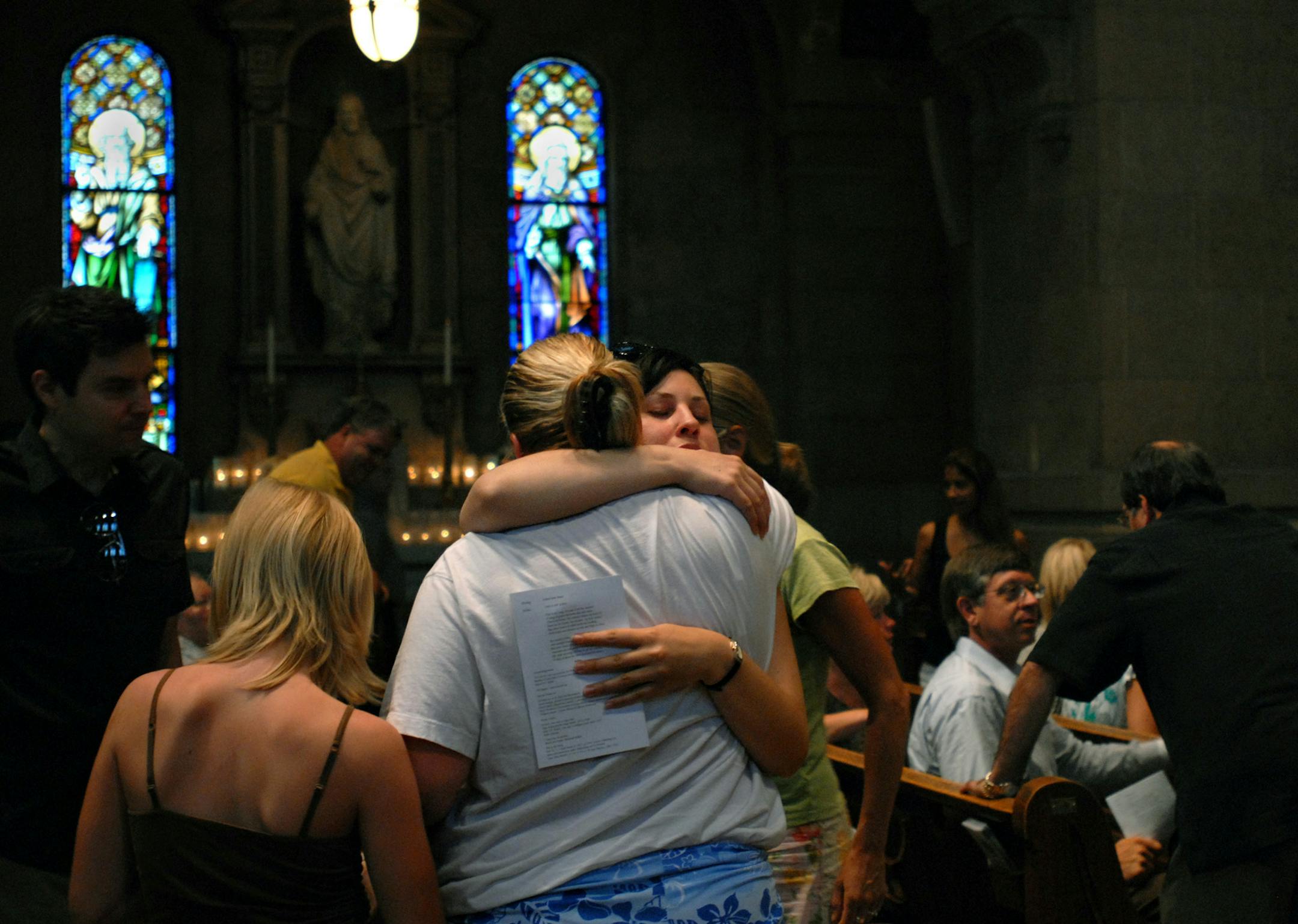 Bridge survivors Kim Dahl and Mercedes Gordon (facing camera) are junior high school friends who were on opposite ends of the bridge when it collapsed last year. They hugged after an Interfaith Service of Remembrance held at the Basilica of Saint Mary. Dahl was the driver of the school bus and Gordon suffered many broken bones. At right is Ron Engebretsen, whose wife, Sherry, died in the collapse. Free public parking is available at the Minneapolis Community and Technical College parking ramp ea