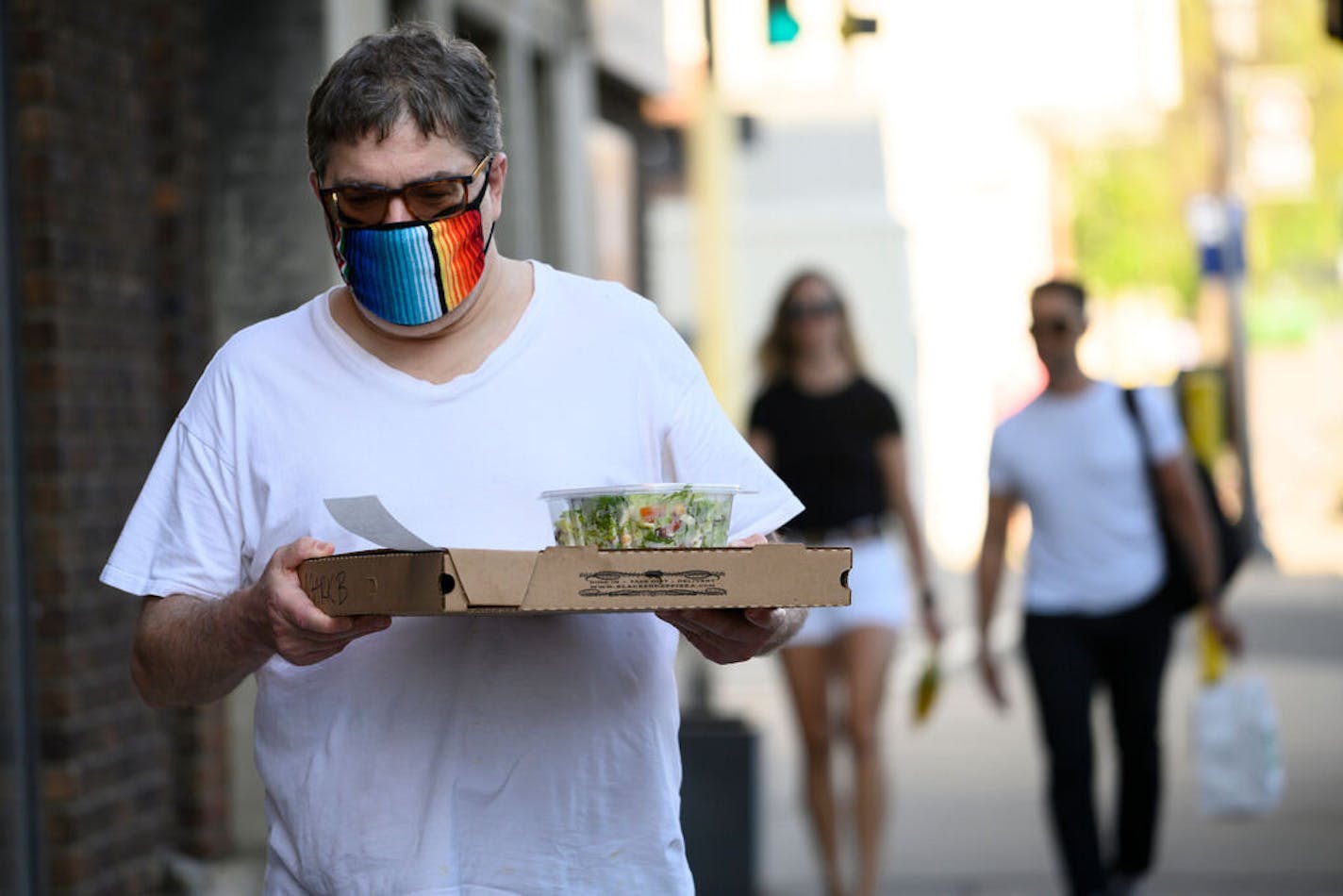 Mark Berman walked back to his North Loop home with a pizza and salad from Black Sheep in May. "I would not go to any place that offers in house dining. I would not even eat outside in a patio setting," said Berman, who is still weary of public settings due to the COVID-19 pandemic. "I follow the science, I don't follow the politics." ]