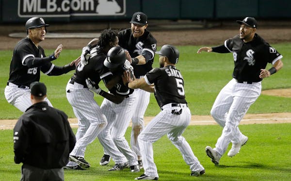 The Chicago White Sox celebrate around Tim Anderson after Anderson drove in the winning run against the Minnesota Twins in a baseball game Wednesday, 