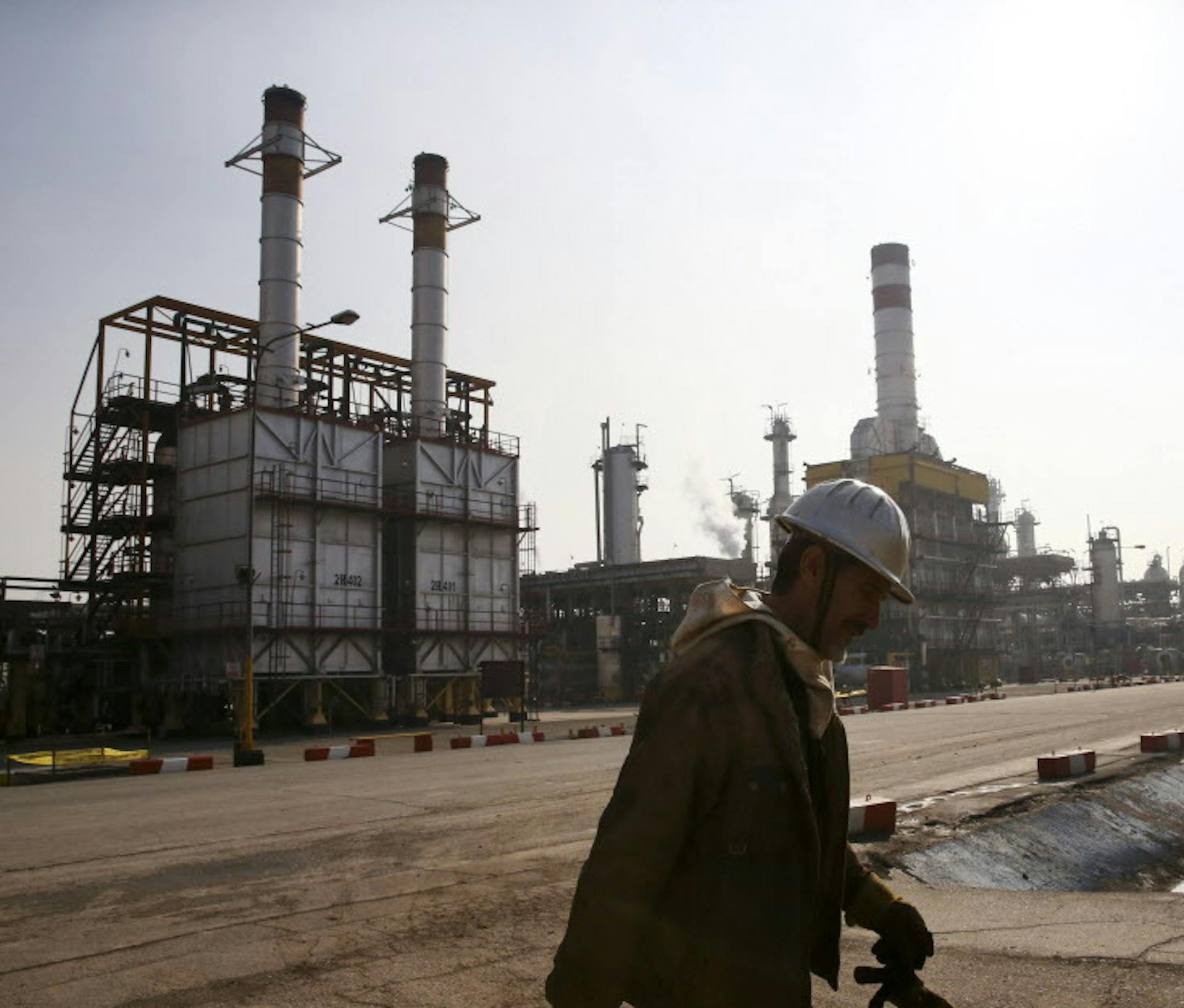 FILE - In this Dec. 22, 2014 file photo, an Iranian oil worker makes his way through Tehran's oil refinery south of the capital Tehran, Iran. Across a Mideast fueled by oil production, low global prices have some countries running on empty and scrambling to cover shortfalls, even as more regional crude is on tap to enter the market.(AP Photo/Vahid Salemi, File)
