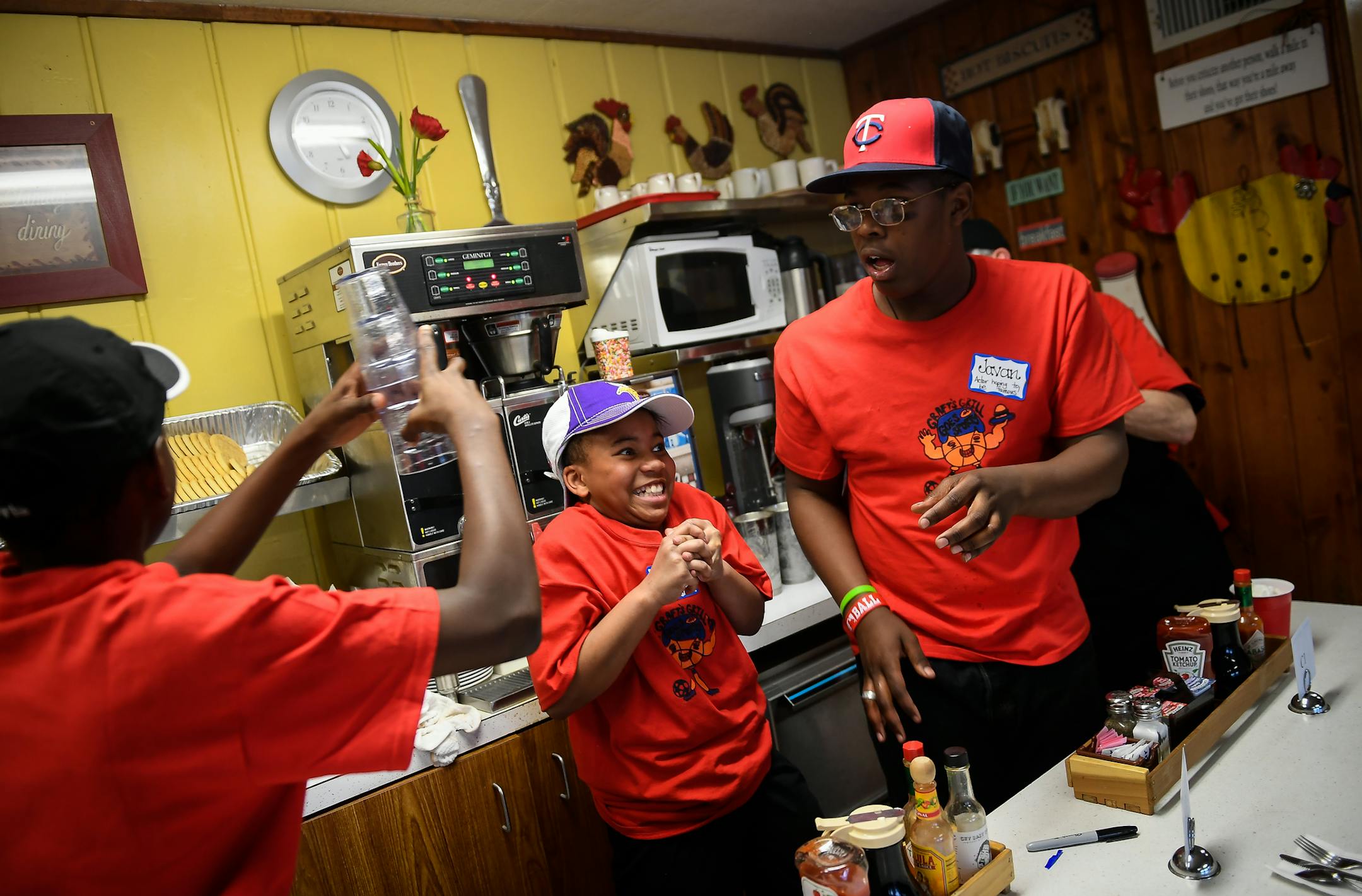 Javan Lawton, 16, right, handed a stack of clean glasses to Nate Agbemadon, 13, as Jessiana Lawton, 10, ducked out of the way with a grin as they worked at Peg's Countryside Cafe Thursday. ] AARON LAVINSKY ï aaron.lavinsky@startribune.com 12 students, with the Interfaith Outreach Neighborhood Program took over dinner restaurant operations at Peg's Countryside Cafe on Thursday, March 30, 2017 in Hamel, Minn. The program, "Graft's Grill Goes Sporty," is meant to teach students real-world, han