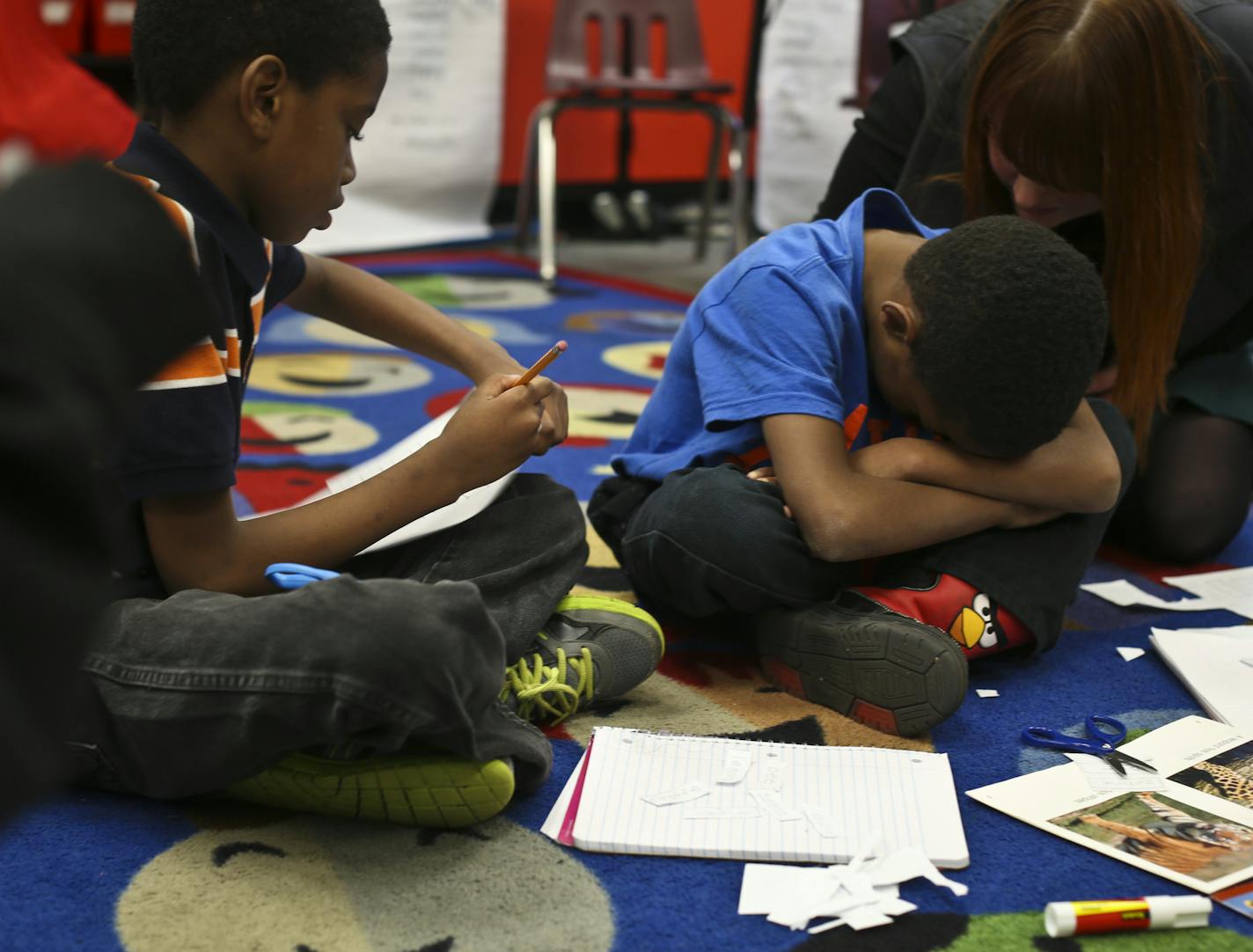 A third grade boy had an emotional moment during a reading exercise before being calmed down by teacher's assistant Sarah Johnson, right, at Hamline Elementary School on Friday, November 8, 2013. Hamline is one of St. Paul's schools that caused an uproar by moving nearly 300 EBD children our of their self-contained units into mainstream classes when the school year began. ] RENEE JONES SCHNEIDER &#x2022; reneejones@startribune.com