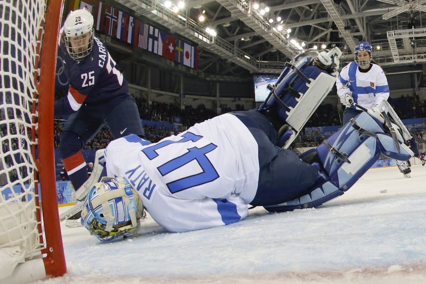 Goalkeeper Noora Raty of Finland falls on the puck to block a who by Alex Carpenter of the Untied States during the third period of the 2014 Winter Olympics women's ice hockey game at Shayba Arena, Saturday, Feb. 8, 2014, in Sochi, Russia.