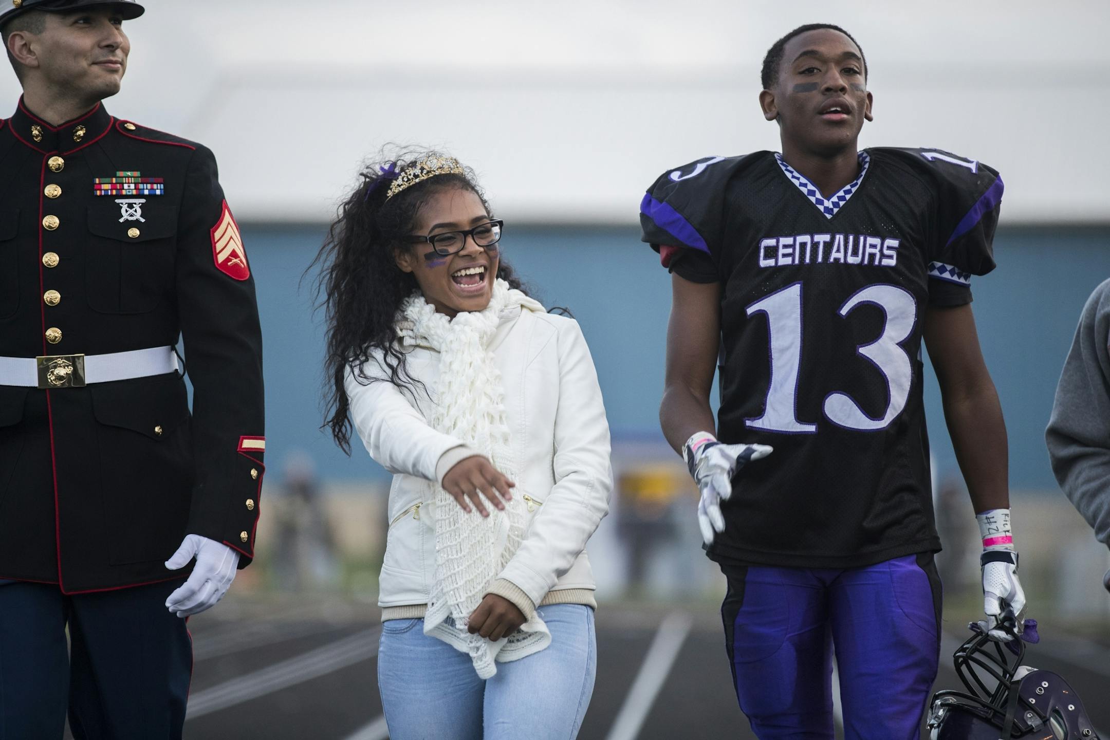 Homecoming queen Gena Burns, center, is escorted by king Kionta Foadoaus, right, and her Marine recruiter Sgt. Mario Rosales, left, during halftime.